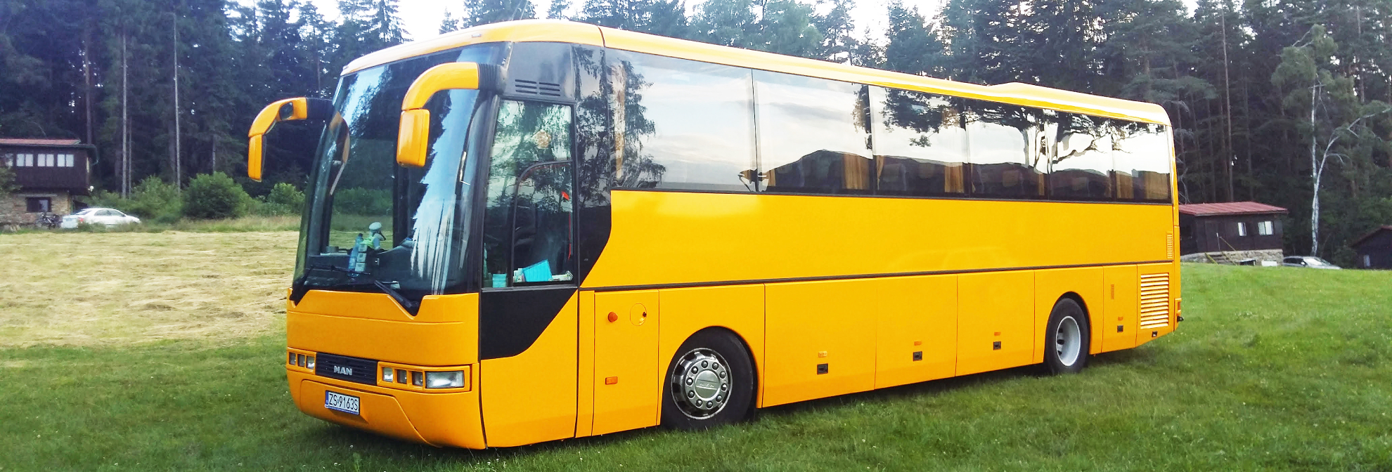 Na zdjęciu widać duży, żółty autobus, którego właścicielem jest firma Miodzio-Bus